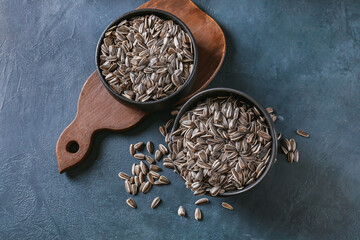 Bowls with sunflower seeds on dark background