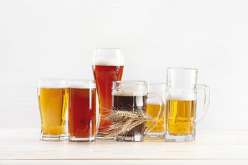 Glasses of different fresh beer on light background