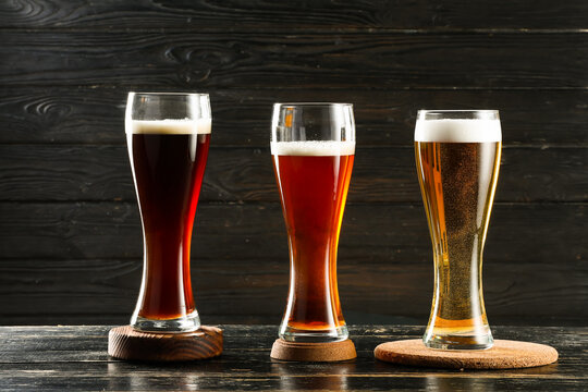 Glasses of different fresh beer on dark wooden background