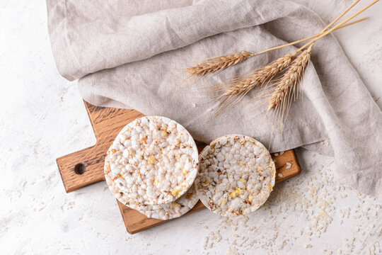 Board with rice crackers on light background