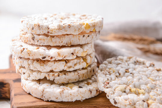 Board with rice crackers on light background, closeup
