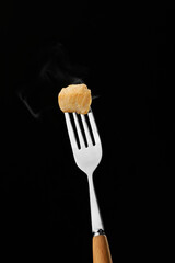 Fork with fried chicken piece on dark background