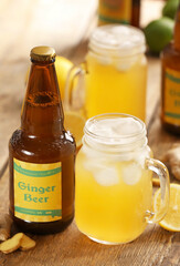 Bottle and mason jar of fresh ginger beer on wooden background