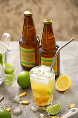 Bottle and glass of fresh ginger beer on grey background