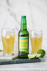 Bottle and glass of fresh ginger beer on light background