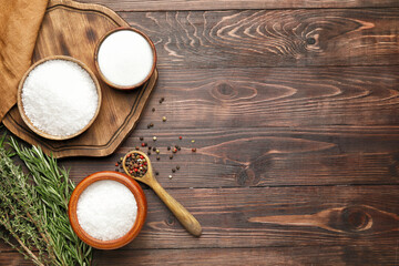 Bowls with salt, herbs and peppercorns on wooden background