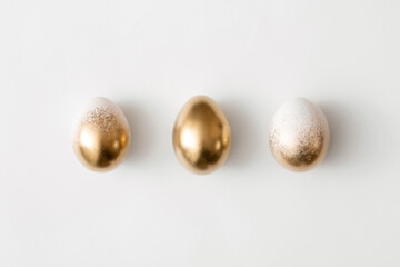 Golden eggs on a white background. Minimal easter concept.