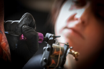 Female tattoo artist making tattoo on a men’s arm