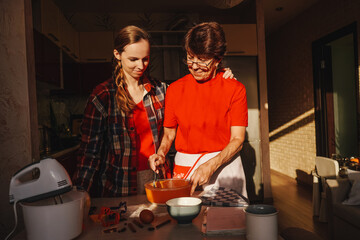 Young woman and senior mother cooking. Sunny.