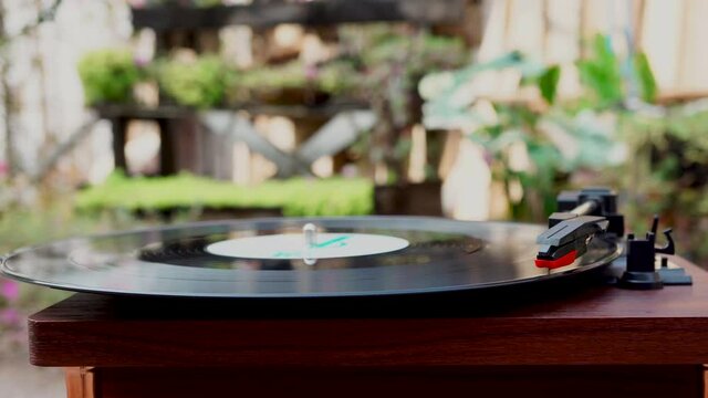 Side view of Turntable is spinning with a phono cartridge on the Vinyl. Vintage music player in the garden.