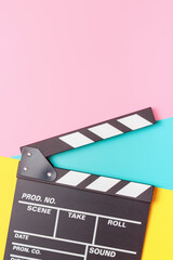 The clapper board on pink, yellow and blue background close-up.