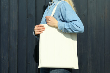 Young woman with stylish eco bag on wooden background