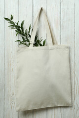 Eco bag with twig on white wooden background