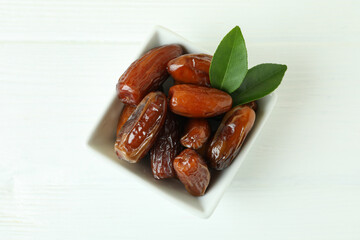 Bowl with dried dates on white wooden table