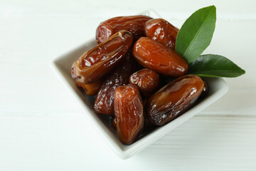 Bowl with dried dates on white wooden table