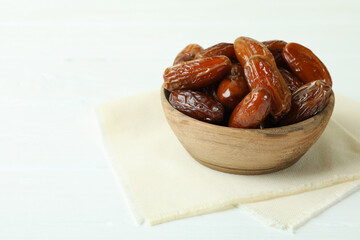 Bowl with dried dates on kitchen napkin on white wooden table