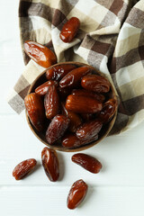 Bowl of dried dates on kitchen napkin on white wooden background