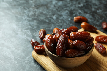 Board with bowl of dried dates on black smokey background