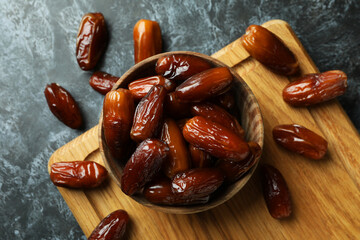 Board with bowl of dried dates on black smokey background