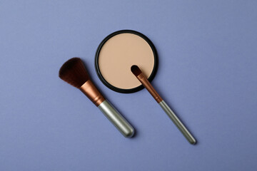 Makeup cosmetics on violet background, top view