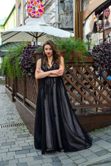 incredibly beautiful full-length woman posing among the city in an amazing black evening dress.