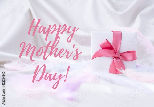 Happy mothers day lettering greeting card. Gift box with pink ribbon dry pink flowers. Bright light pastel concept.