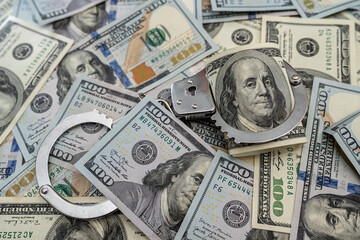 close up of metal handcuffs on hundred dollar banknotes