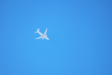 White airplane flying in the clear blue sky. Commercial plane, bottom view