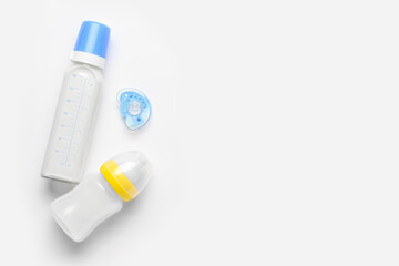 Bottles of milk for baby and pacifier on white background