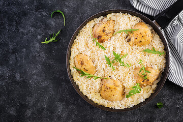 Rice with chicken thighs, pilaf  in skillet on dark background. Top view, above, copy space