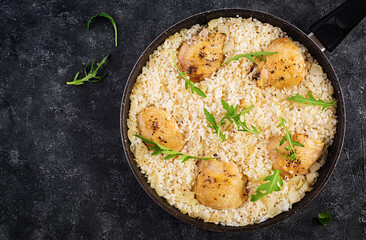 Rice with chicken thighs, pilaf  in skillet on dark background. Top view, above, copy space