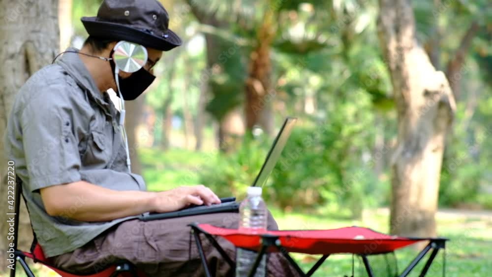 Poster man using laptop computer in garden background and relaxing on holiday