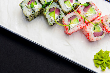 Ebiko black caviar adn red caviar sushi rolls - japanese food style. Served on a white plate over black background.