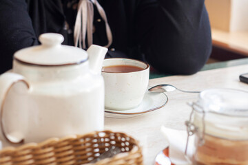 Tea is served on the table, teapot, cup and dessert