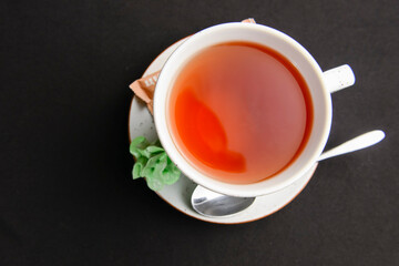 Cup of tea isolated on a black background. Black tea in a white cup, tea time.