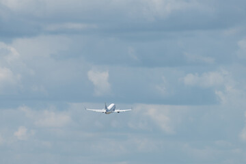 A modern white jet airliner takes off from the airport against the backdrop of a cloudy sky.