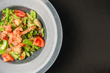 Tuna and vegetable salad in a plate over black background. Healthy food, eating out concept.