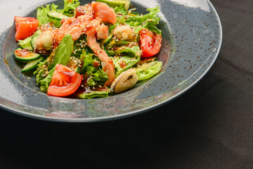 Tuna and vegetable salad in a plate over black background. Healthy food, eating out concept.