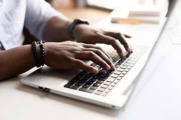 Close up image of male hands with accessories typing text on the laptop keyboard, working, responding to client e-mail, buying ordering items online. Electronics and modern wireless technology concept