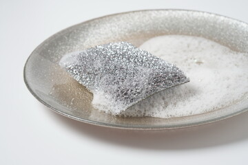 Silver cleaning sponge in soap foam on a plate