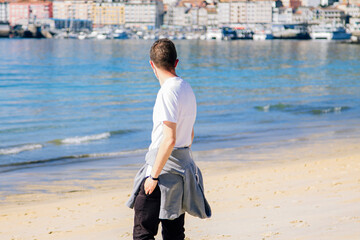 man with medical mask in protection of the coronavirus in the new normal walking on the beach