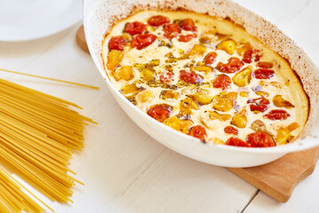Trending viral recipe of baked tomatoes and feta with pasta, Fetapasta on a white wooden background. New, popular dinner dish, Top view, copy space..