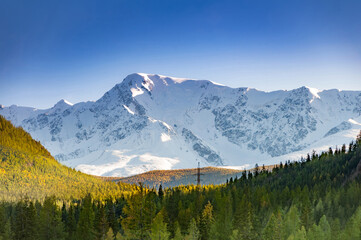 Fototapeta premium Scenic aerial view over snow capped mountain range, surrounded by siberian forest. Altai autumn landscape, Russia