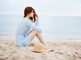 Fototapeta na wymiar Romantic woman sitting with hat and blue dress sand sea