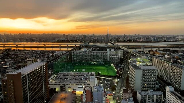 TOKYO, JAPAN : Aerial sunset CITYSCAPE of TOKYO and residential area. View of river and buildings at downtown area. Japanese metropolis and lifestyle concept. Time lapse tracking shot dusk to night.
