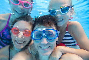Naklejka premium underwater photo of little boy with his family swimming in pool