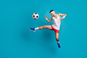 Full length photo of crazy football player kick ball in jump wear white tank-top isolated over blue...