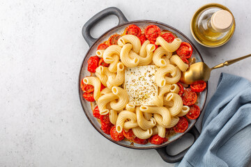 Cooking baked feta pasta. Cooked pasta with baked feta cheese, and cherry tomatoes, before mixing...