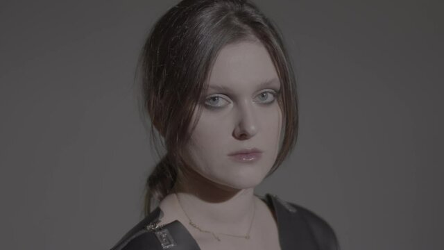 Dark hair woman posing in the black dress in the studio lights. Young attractive woman wearing a black dress. Ungraded video.