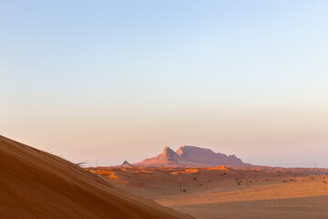 Fototapeta na wymiar Sunset over Fossil Rock mountain ridge and golden desert, Sharjah, United Arab Emirates.